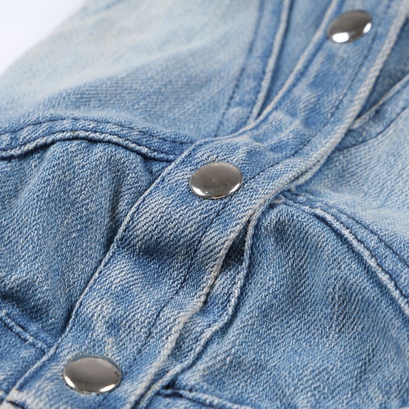 Close-up of blue denim fabric with metal buttons on a white background