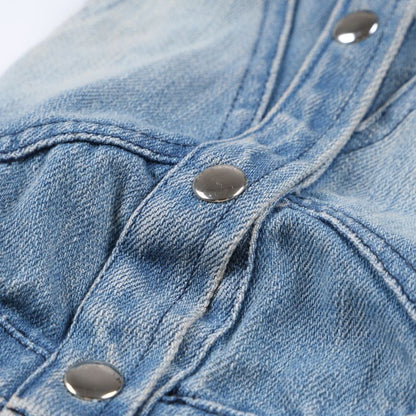 Close-up of blue denim fabric with metal buttons on a white background