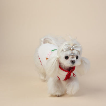 Small white dog wearing a festive outfit with a red scarf and white hat on a beige background