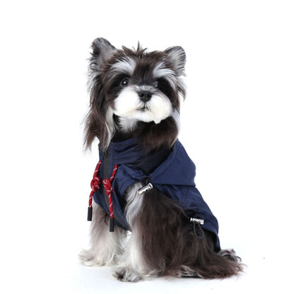 Dog wearing a navy blue raincoat with red accents on a white background