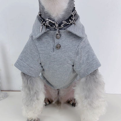 Dog wearing a gray chrome heart polo with a white background