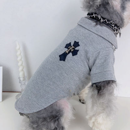 Dog wearing a gray chrome hearts with a cross design on a white background
