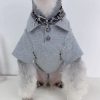 Dog wearing a gray chrome heart polo with a white background