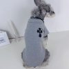 Dog wearing a gray chrome heart polo with a black cross design on a white surface.