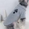 Dog wearing a gray chrome hearts with a cross design on a white background
